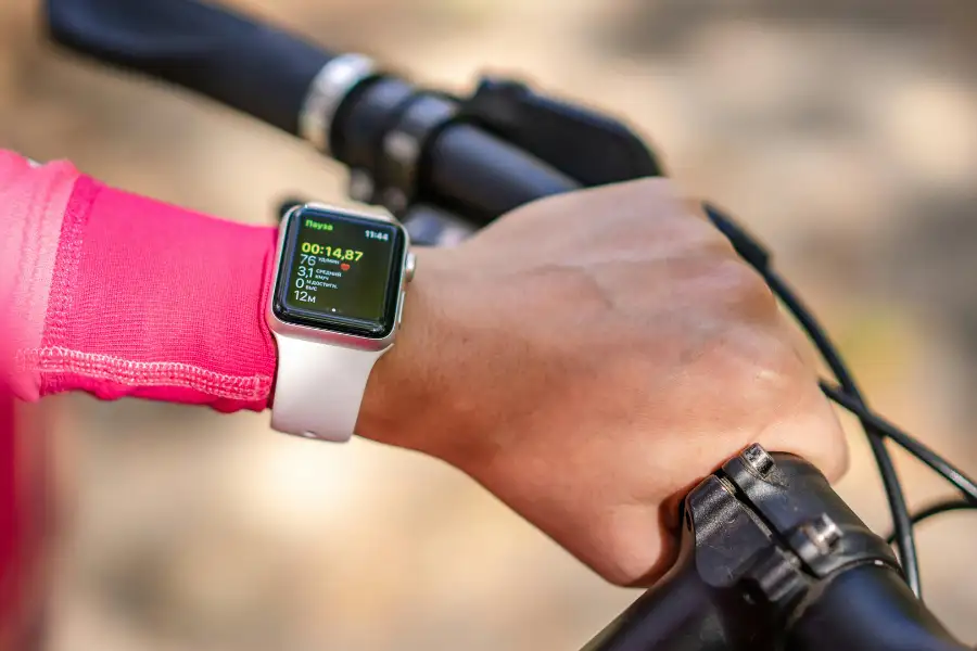 Relógio esportivo de alta tecnologia no pulso, monitorando dados de treino na bicicleta.