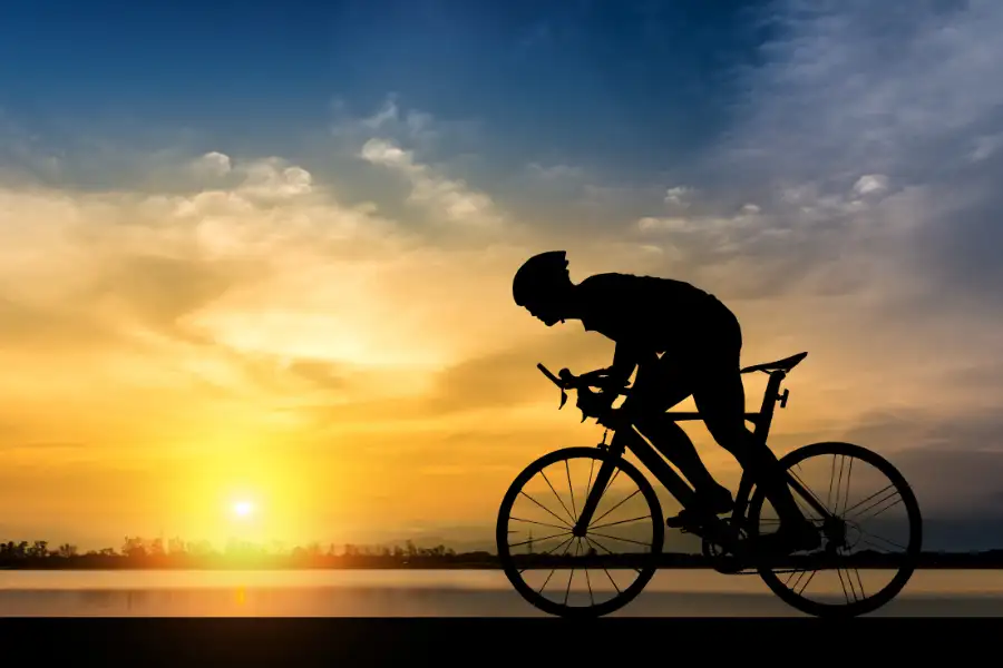 Ciclista em silhueta ao pôr do sol. Acessórios essenciais para performance no ciclismo.