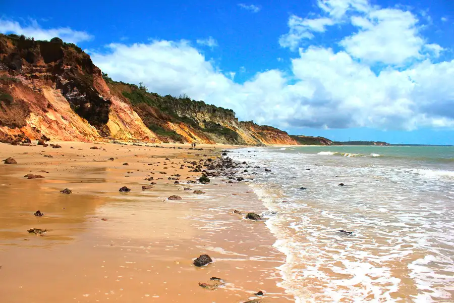 Praia do Litoral Norte com águas cristalinas. Falésias coloridas e céu azul com nuvens. Paraíso tropical.